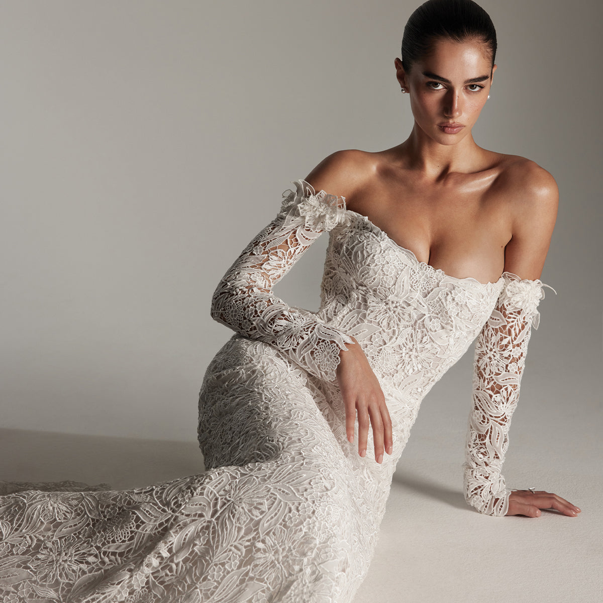 Model wearing Monique Lhuillier Spring 2026 Bridal white Chiffon Guipure Lace Off-the-shoulder Autry trumpet gown with detachable long sleeves``1