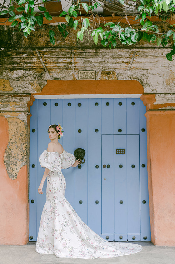 Woman wearing Monique Lhuillier Fall 2022 fitted ivory and floral print Amalia gown with billowed sleeve