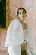Woman wearing Monique Lhuillier Fall 2022 white fitted floral organza Delilah gown with billowing Delilah jacket