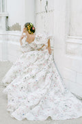 Woman wearing Monique Lhuillier Fall 2022 ivory and floral printed Alice bodice with billowed sleeve and matching Alice ball skirt
