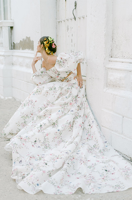 Woman wearing Monique Lhuillier Fall 2022 ivory and floral printed Alice bodice with billowed sleeve and matching Alice ball skirt