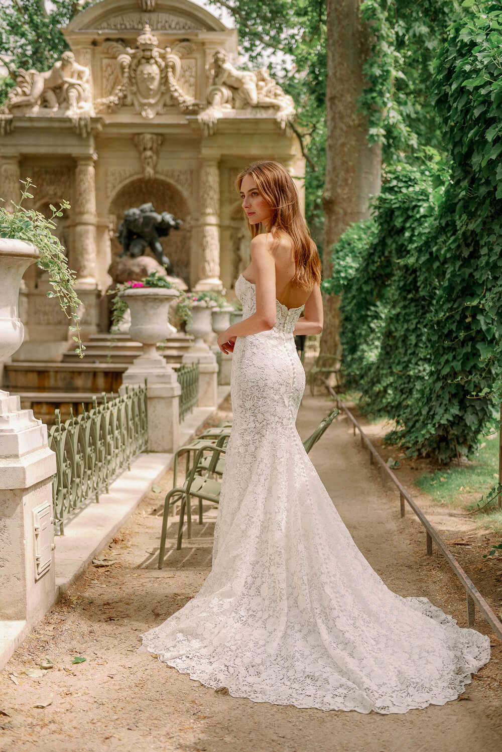 Woman wearing Monique Lhuillier Fall 2023 Bliss white lace strapless sweetheart fitted BL23202 gown with long train