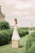 Woman wearing Monique Lhuillier Spring 2024 Bliss white embroidered lace BL24013 trumpet gown with detachable off-the-shoulder lace sleeves