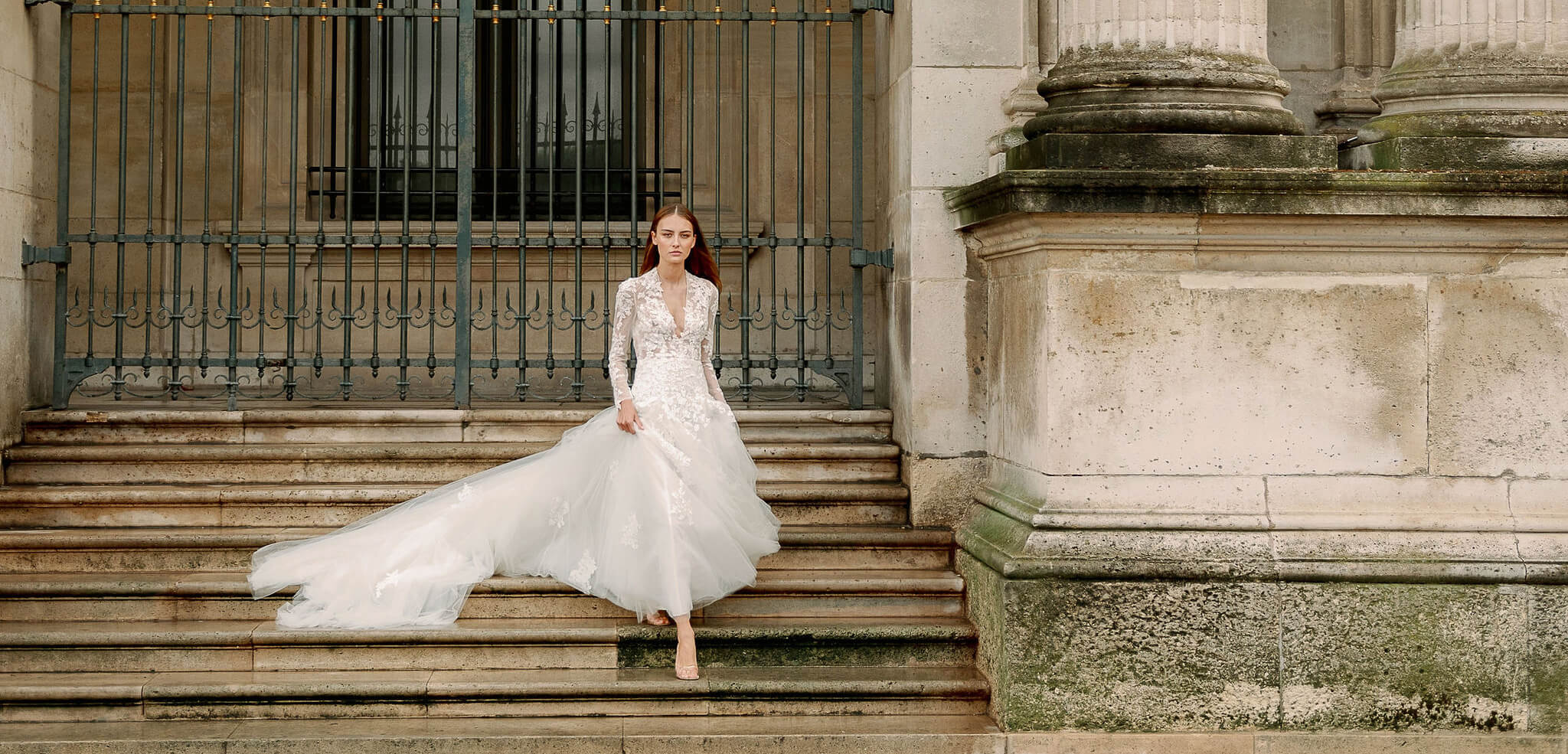 Woman wearing Monique Lhuillier Fall 2023 Bliss long sleeve v-neck white embroidered tulle a-line BL23203 gown