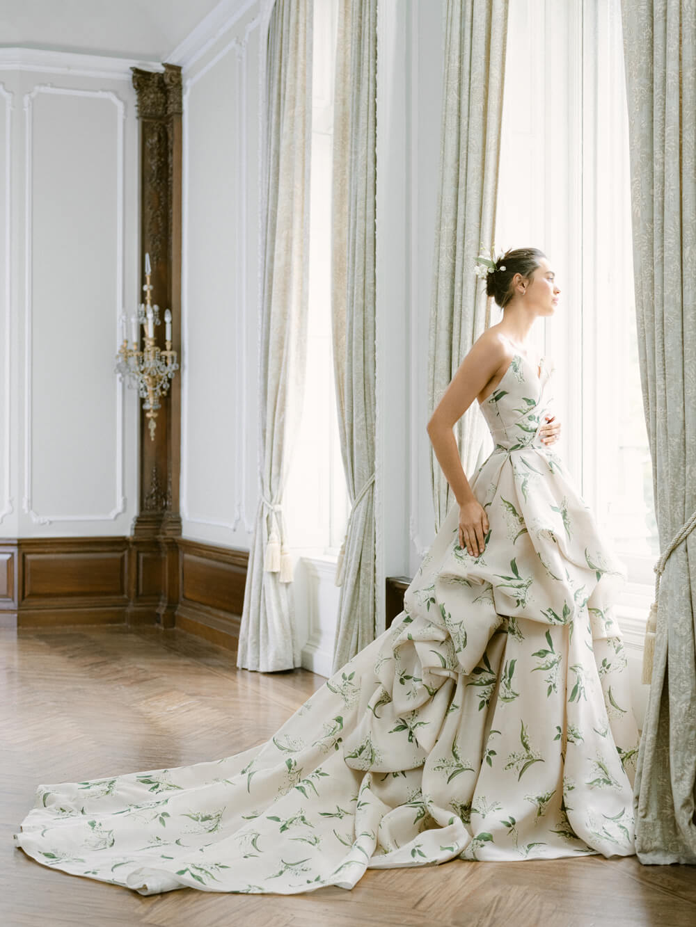 Woman in window wearing Monique Lhuillier Fall 2021 strapless ivory and green lily of the valley printed Sweetness ballgown