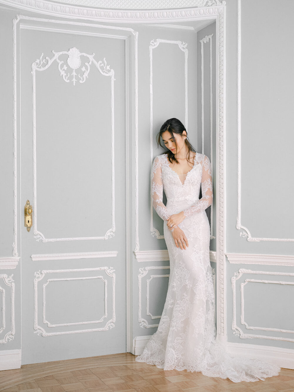 Woman wearing white fitted trumpet lace Monique Lhuillier Fall 2021 Valentine gown with lace long sleeve Valentine jacket