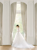 Woman in window wearing white Monique Lhuillier Fall 2021 Lily of the Valley tulle ball gown with green 3-D embroidery and matching jacket