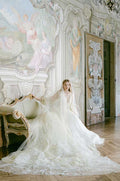 Woman sitting in yellow and green floral print Monique Lhuillier Spring 2022 Buttercup a-line gown with billow sleeves and long train