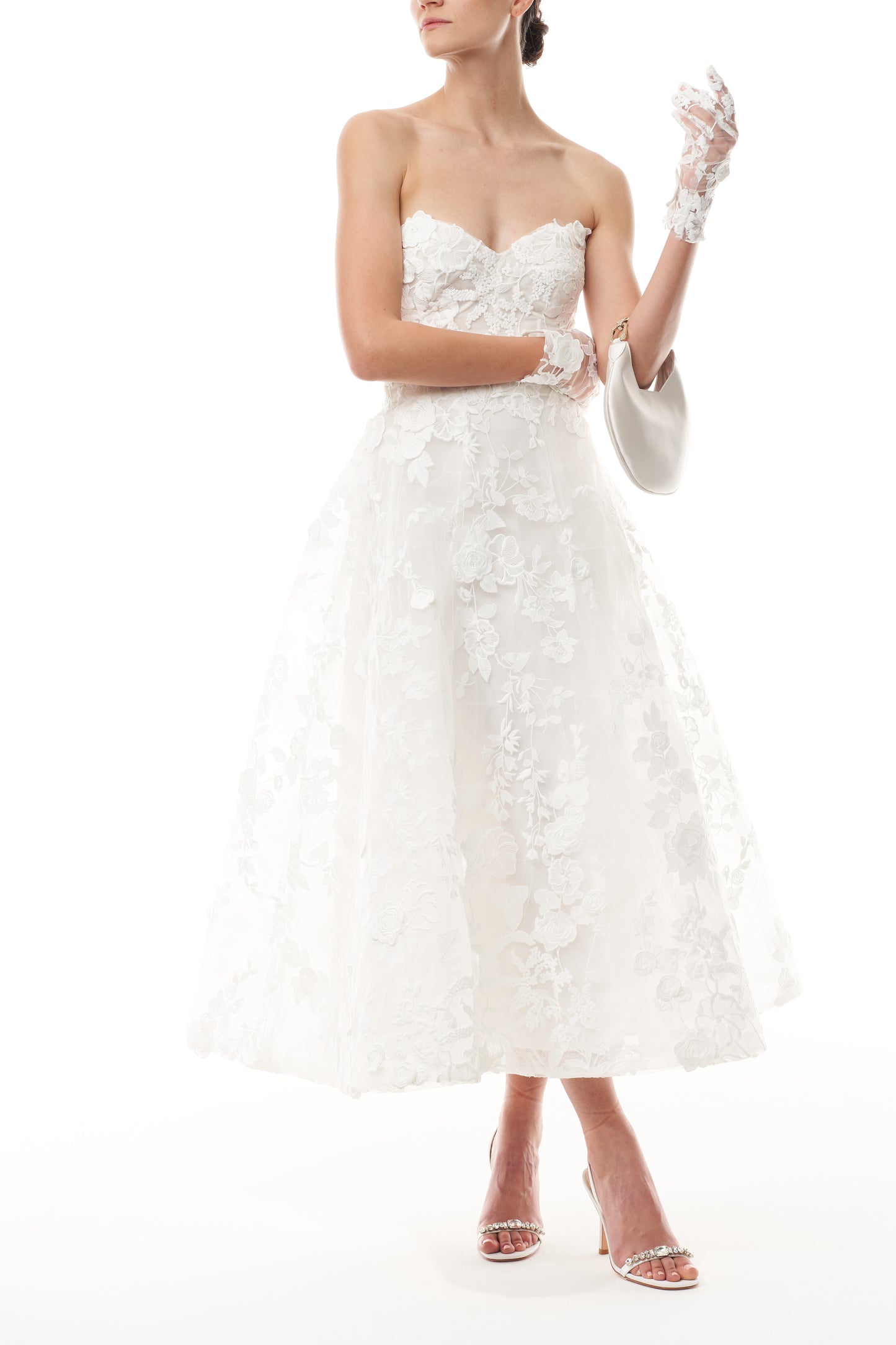 Monique Lhuillier Fall 2024 tea-length, strapless dress in silk white3D lace with full skirt and fitted sweetheart bodice - front with Demi bag and lace gloves.