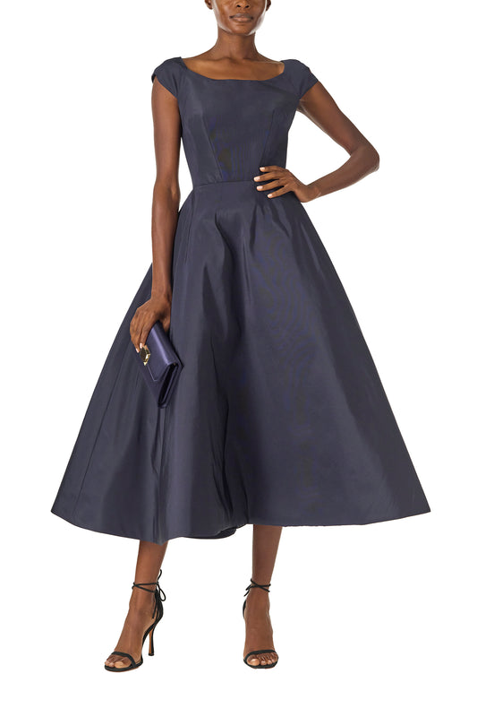Satin evening envelope clutch with snap closure and gold optional strap in Navy- on model wearing tea length navy dress.