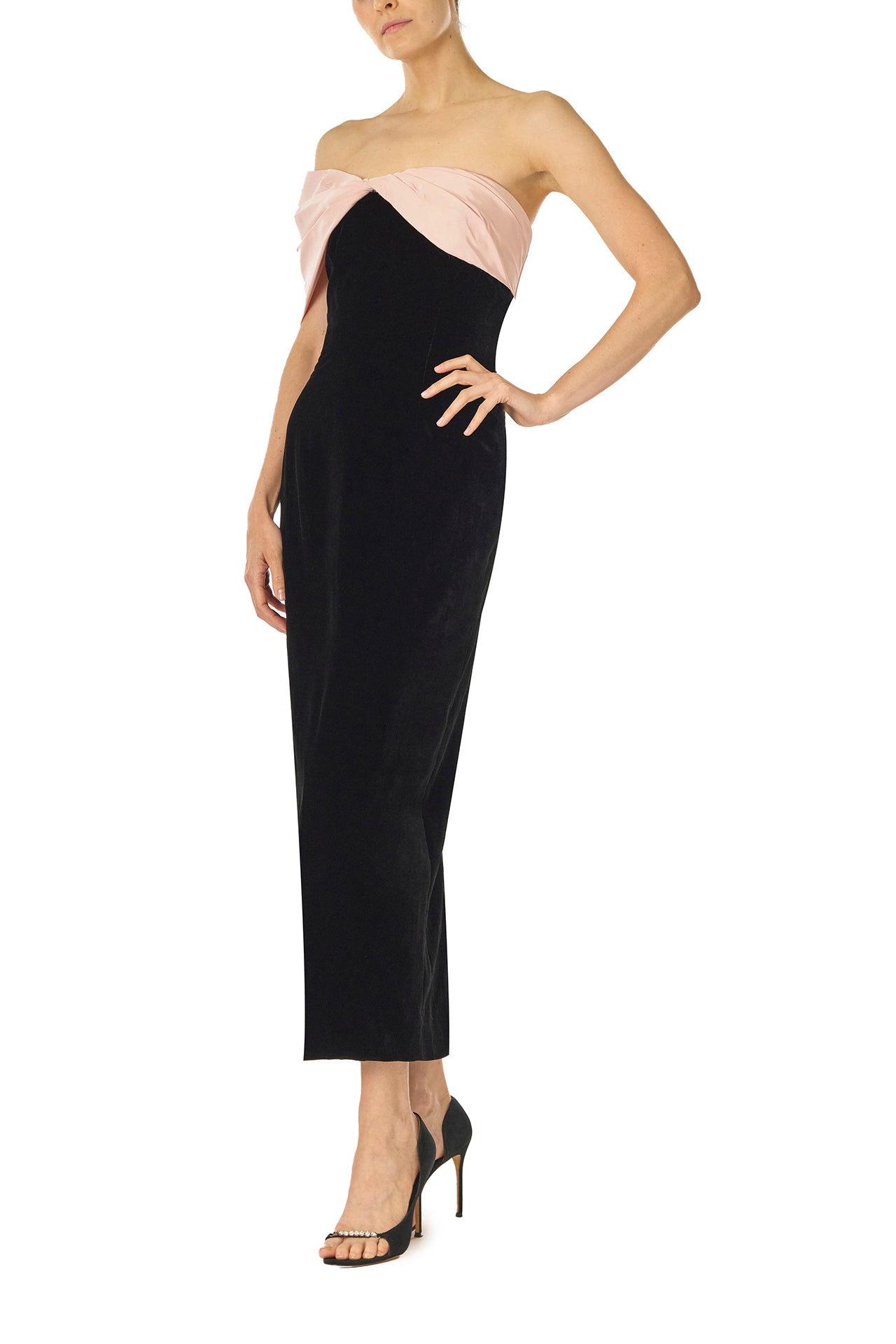 Monique Lhuillier Fall 2024 black velvet off the shoulder sheath dress with pale blush draped, asymmetric twist detail at neckline - left side.