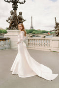 Woman wearing Monique Lhuillier Spring 2024 Bliss white embroidered lace and mikado BL24014 trumpet gown with lace long sleeve jacket