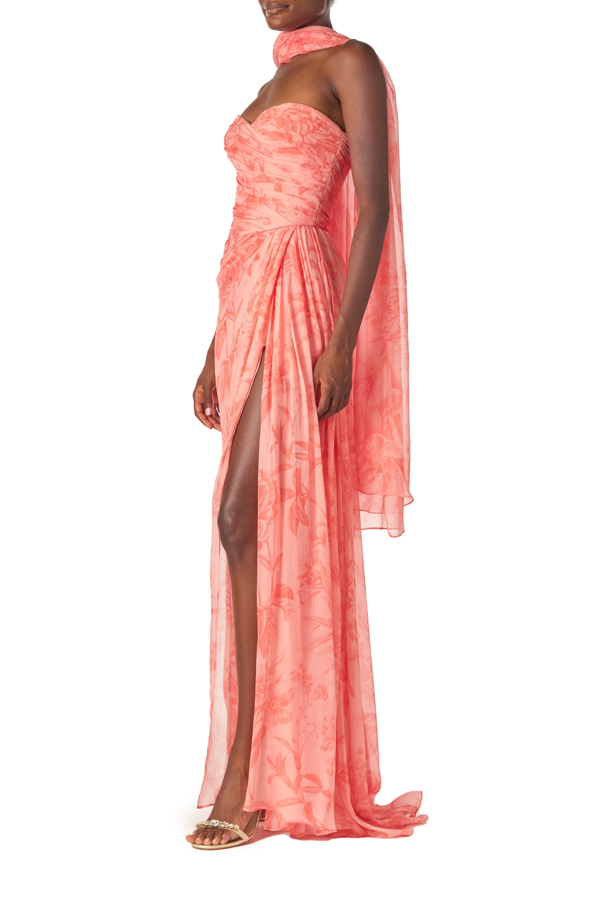 Monique Lhuillier Spring 2025 Strapless floral chiffon gown with draped, sweetheart neckline and detached neck scarf in Rosette Coral color - left side with leg slit.