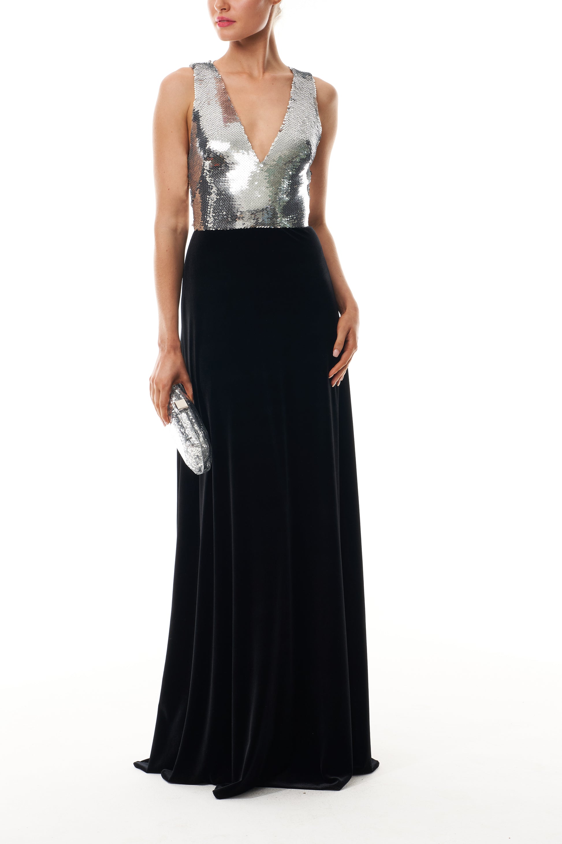 Monique Lhuillier Fall 2025 v-neck gown with silver sequin bodice and noir velvet skirt - front with Viv clutch.
