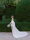 Woman wearing Monique Lhuillier Fall 2024 ivory printed gazar Avery bubble hem cocktail gown with detachable draped sleeve and cape train