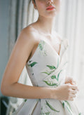 Woman in window wearing Monique Lhuillier Fall 2021 strapless ivory and green lily of the valley printed Sweetness ballgown