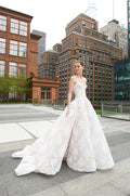 Woman wearing Monique Lhuillier Spring 2018 white corseted dropped waist lace Alexandra ball gown with full circular skirt