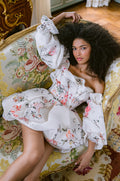 Woman wearing Monique Lhuillier Fall 2023 white and floral printed Bon Bon cocktail dress with bubble hem skirt and billowed sleeves
