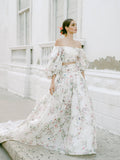 Woman wearing Monique Lhuillier Fall 2022 ivory and floral printed Alice bodice with billowed sleeve and matching Alice ball skirt