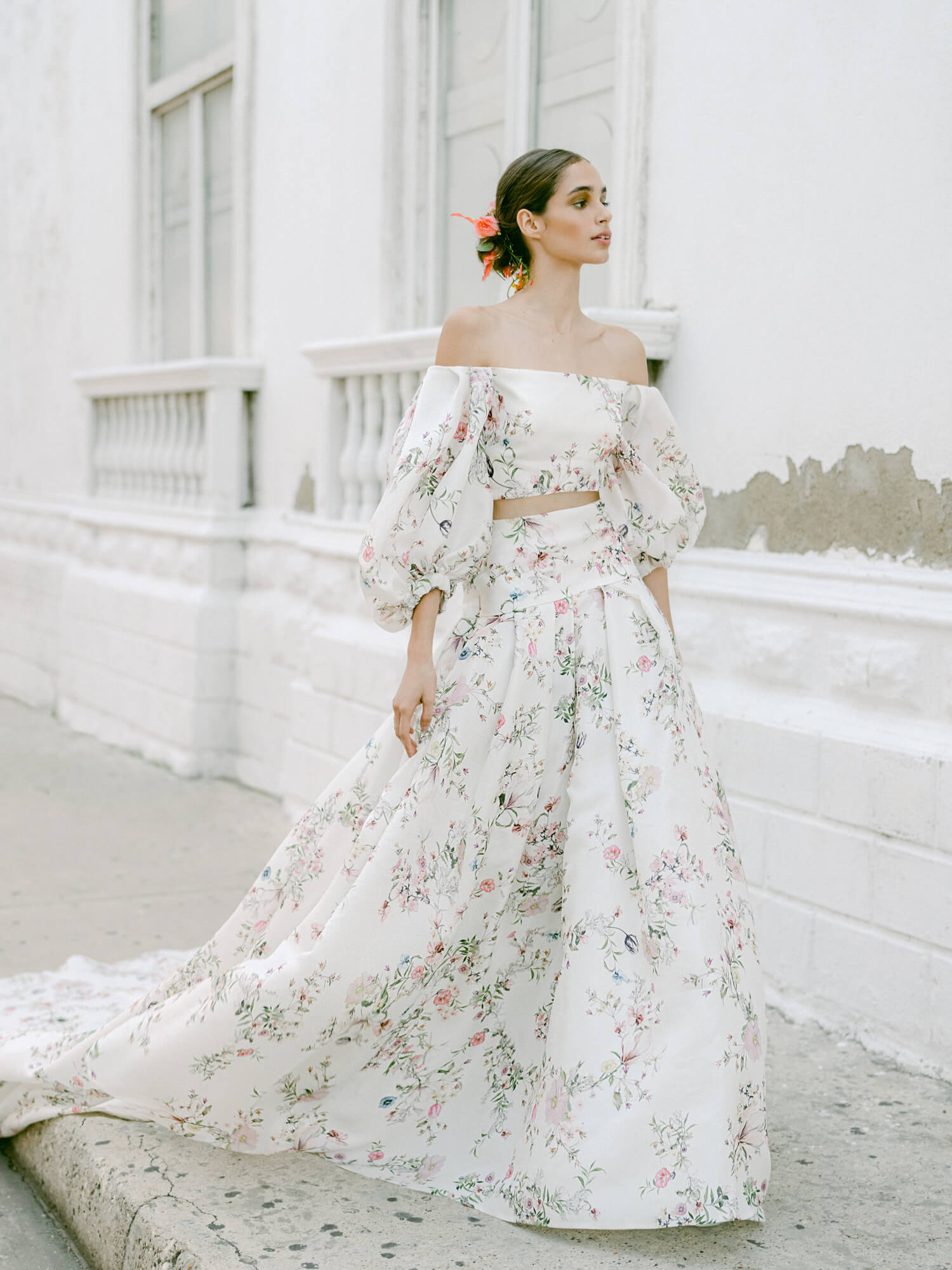 Woman wearing Monique Lhuillier Fall 2022 ivory and floral printed Alice bodice with billowed sleeve and matching Alice ball skirt