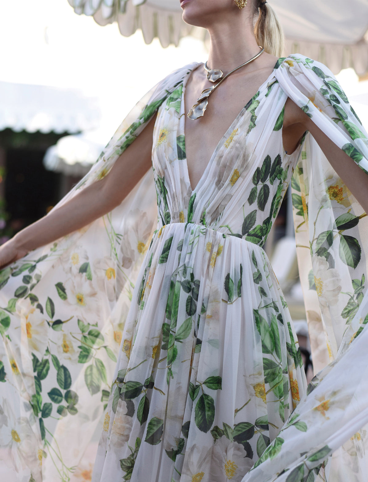 Monique Lhuillier Spring 2025 silk white and floral printed chiffon v-neck gown with attached cape.