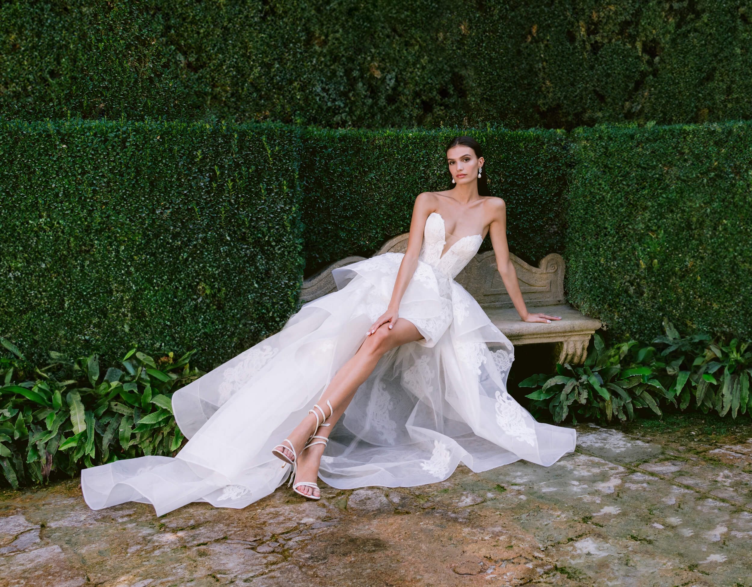 Woman wearing Monique Lhuillier Fall 2024 white lace strapless Harlow cocktail gown with lace Madame Butterfly overskirt 