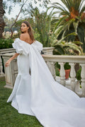 Woman wearing white Monique Lhuillier Spring 2021 mikado fitted off-the-shoulder Admire gown with Admire cape