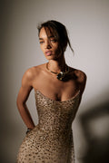 Monique Lhuillier Spring 2026 lookbook image - model wearing gold crystal embroidered tulle scoop neck strapless gown