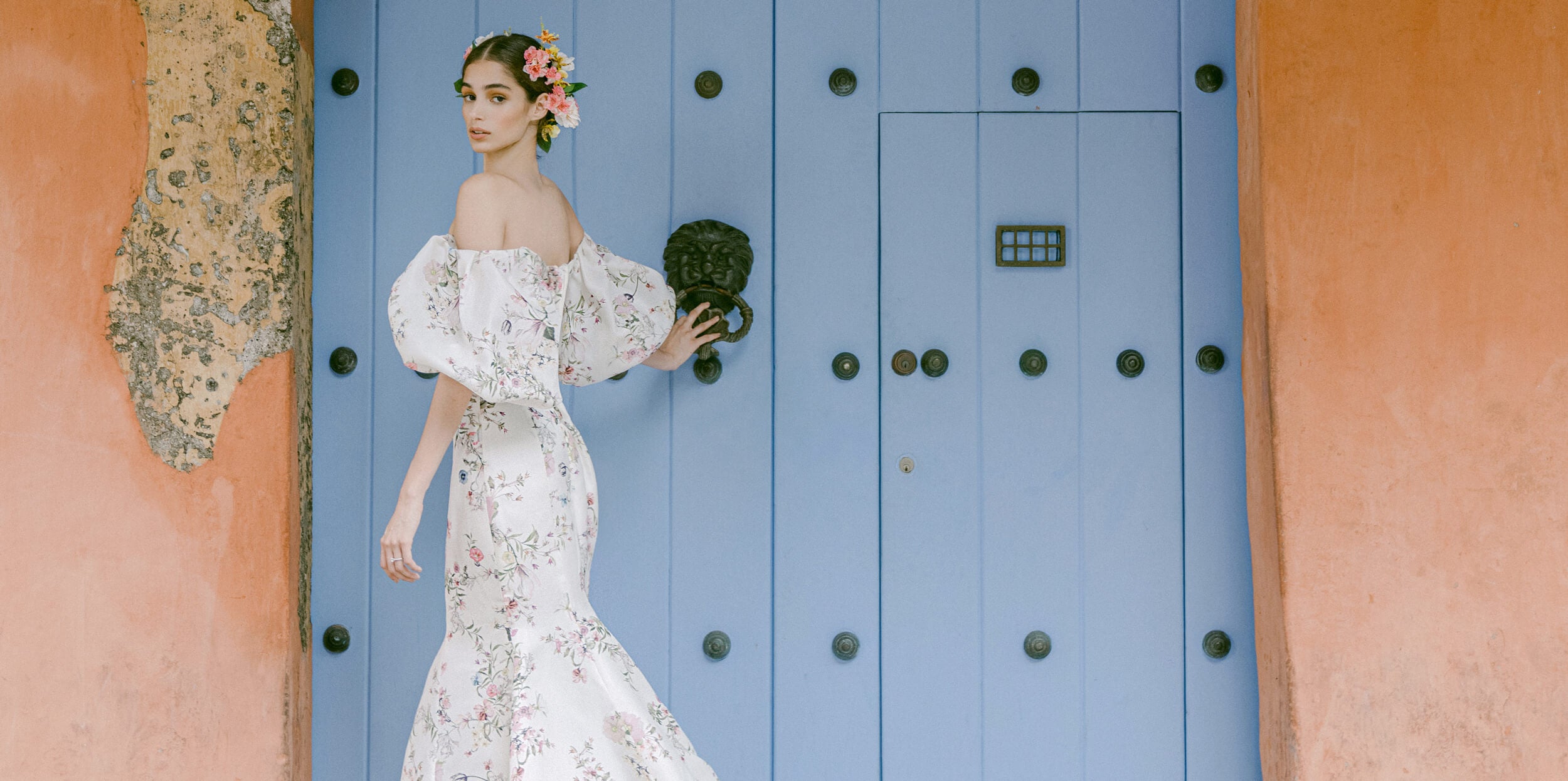 Woman wearing Monique Lhuillier Fall 2022 fitted ivory and floral print Amalia gown with billowed sleeve