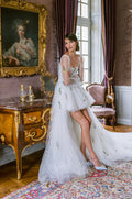 Woman wearing Monique Lhuillier Fall 2023 white scoop neck high-low tulle Provence ballgown with billowed sleeve and multicolor embroidery