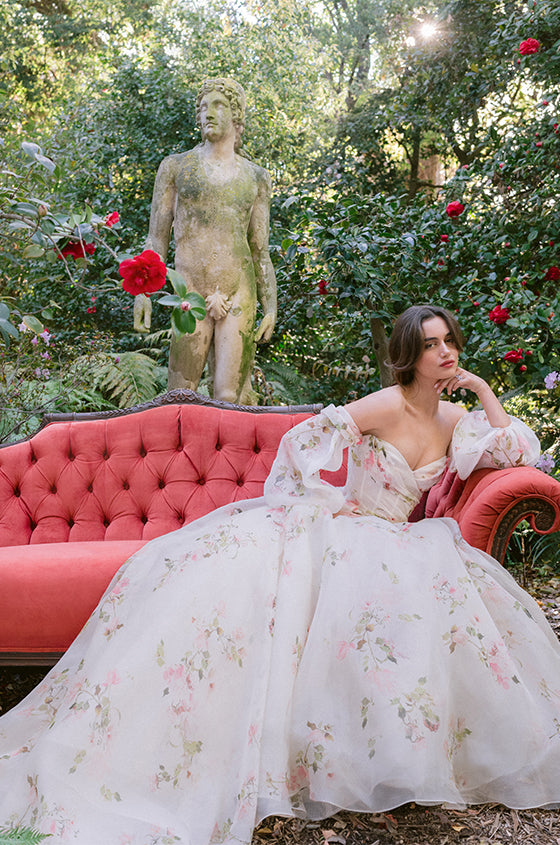 Woman wearing Monique Lhuillier Spring 2024 dropped waist white and floral printed Barrington draped ballgown and detachable billow sleeves