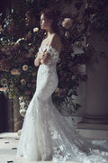 Woman wearing Monique Lhuillier Fall 2019 white fitted embroidered applique Willow gown with off-the-shoulder cap sleeves and long train