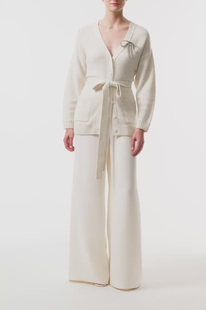 Monique Lhuillier Fall 2025 long sleeve cardigan in ivory sequin cashmere with bow brooch and self-tie belt - video.