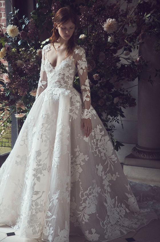 Woman wearing Monique Lhuillier Fall 2019 white and blush floral embroidered applique Maeve ballgown with matching long sleeve jacket