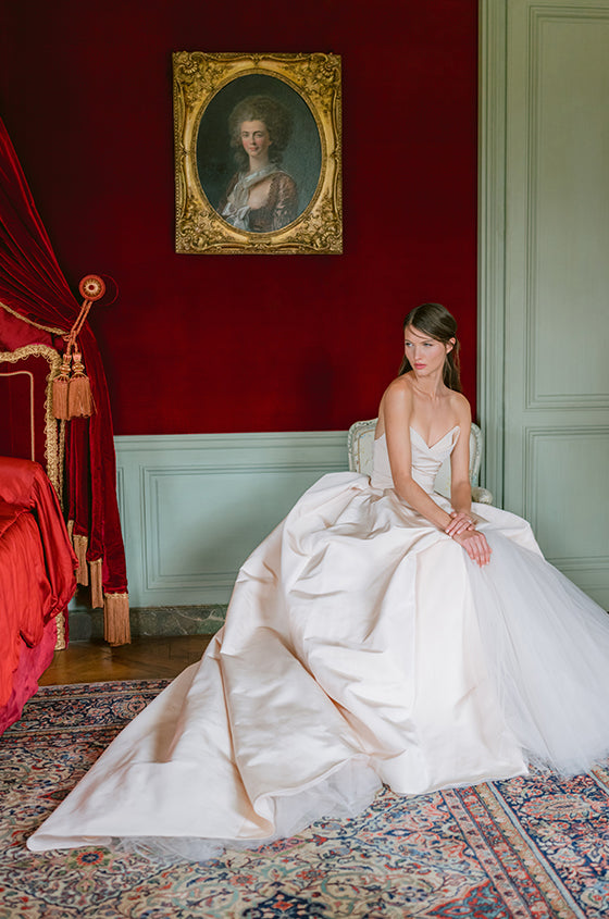 Woman wearing Monique Lhuillier Fall 2023 blush Issa strapless silk faille ballgown with origami neckline and exposed tulle skirt