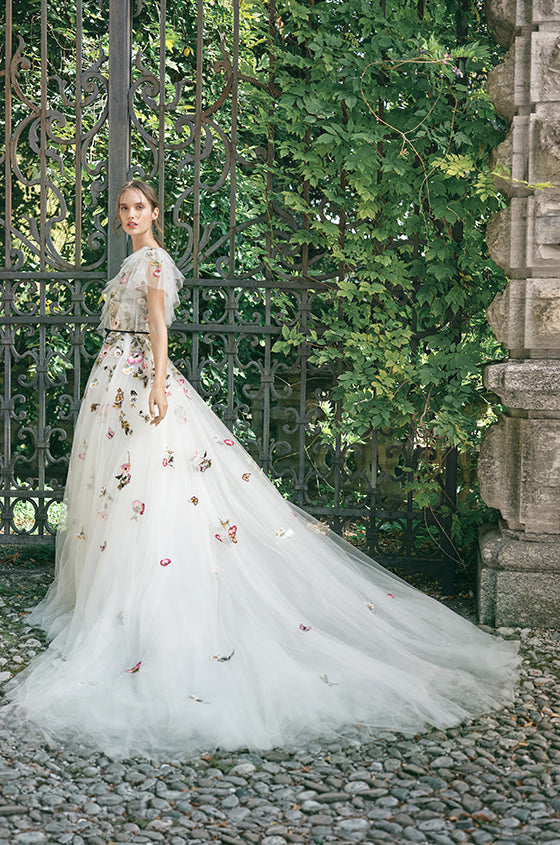 Woman wearing Monique Lhuillier Fall 2020 Wonder a-line gown with multi-colored floral embroidered tulle and ruffle detail at neckline
